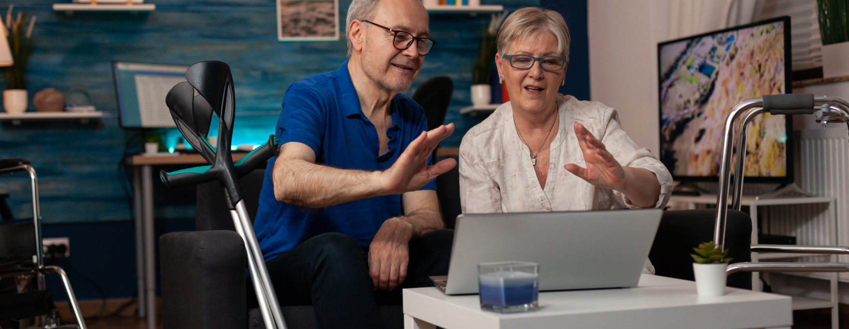 seniors waving at video call camera on laptop